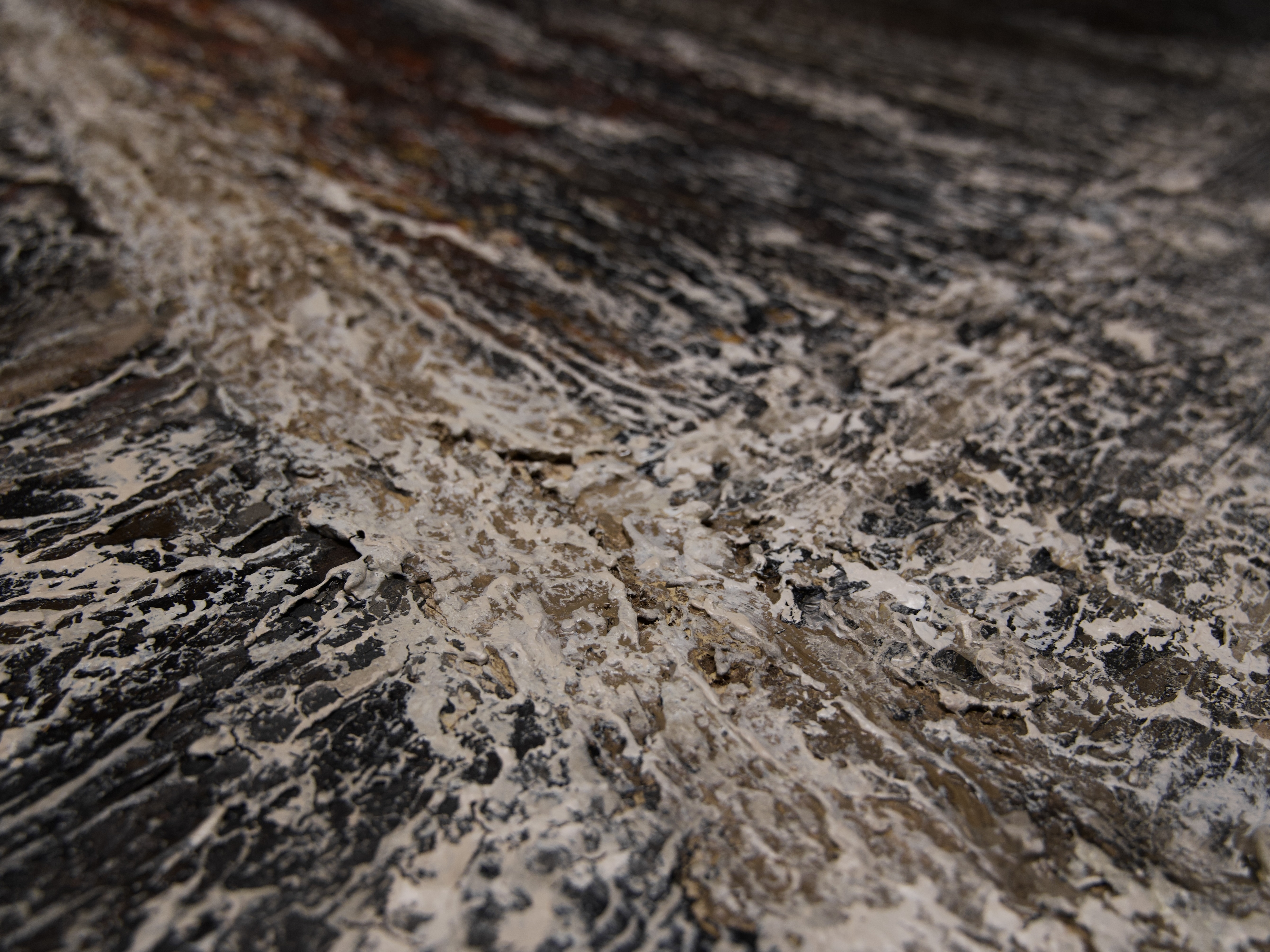 Close-up of textured painting surface with layered paper clay, sand, and pigment